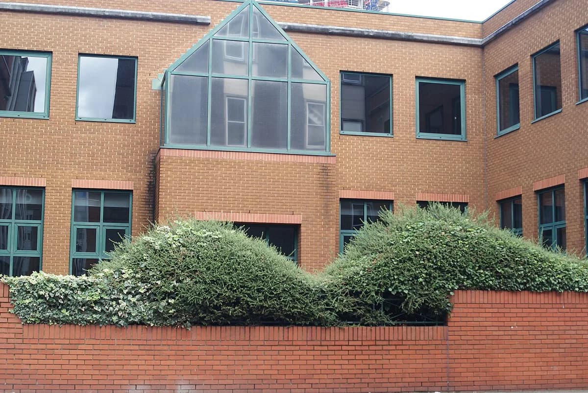 Brick office building with many windows and a glass-roofed central section in London.