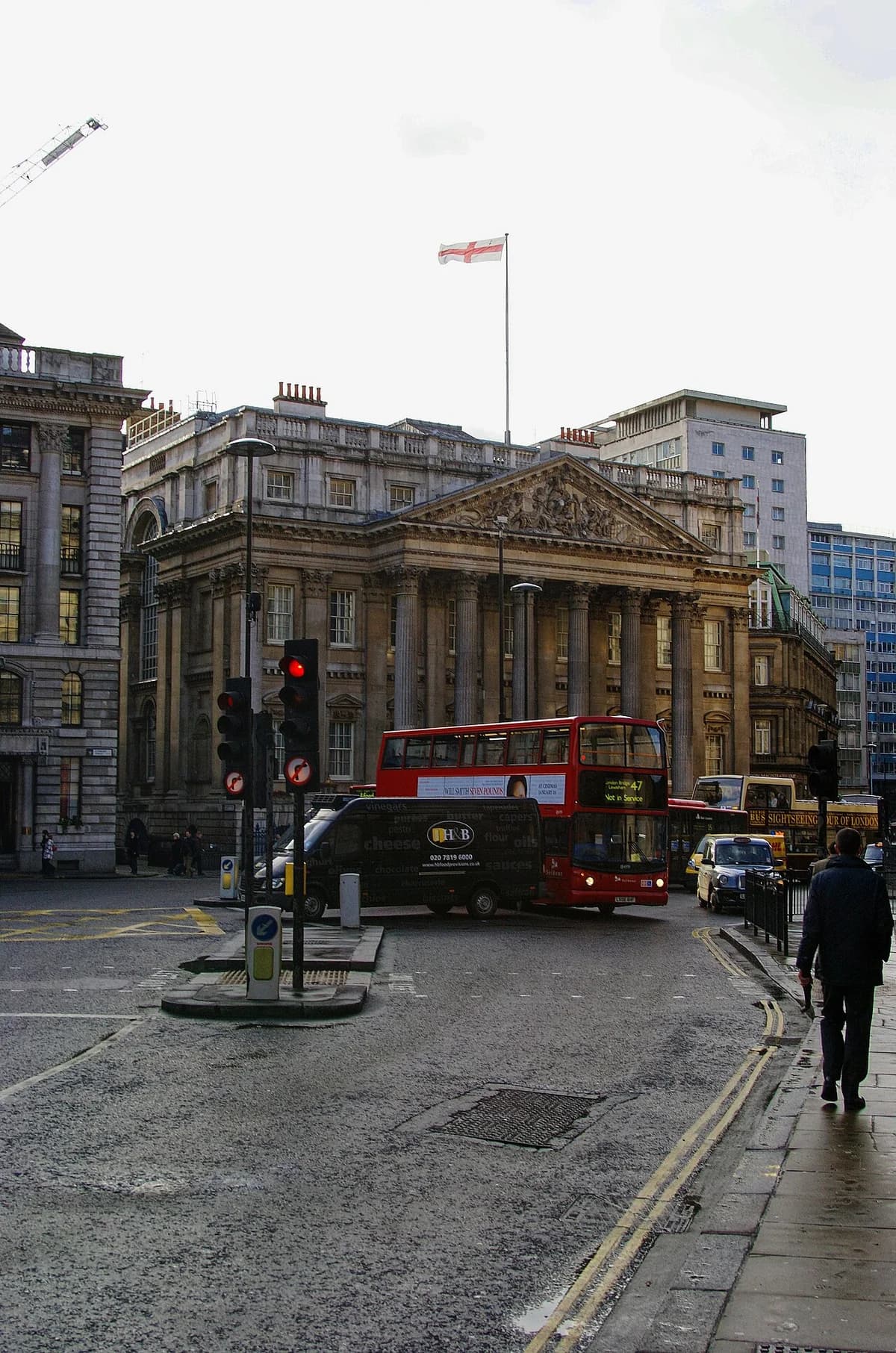 Mansion House in London with traffic and buses on the street.